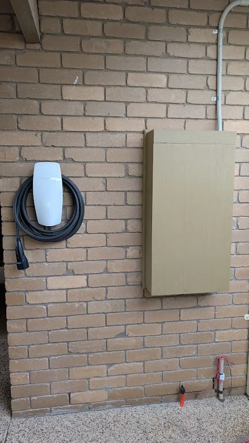 Tesla Wall Connector EV charger installed on a brick wall beside the meter box, Geelong